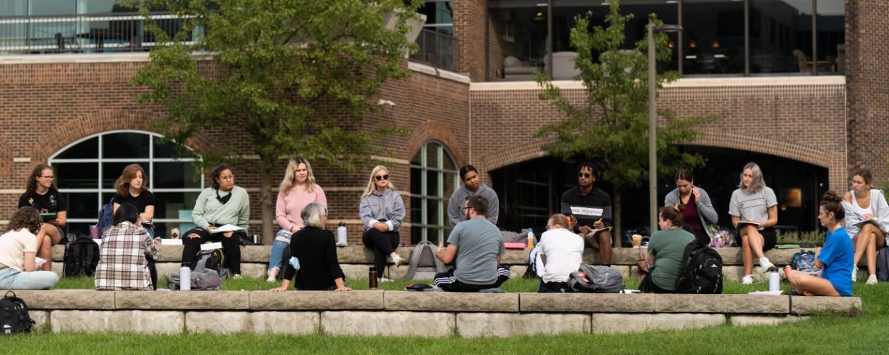 Students sitting on seats by the pond